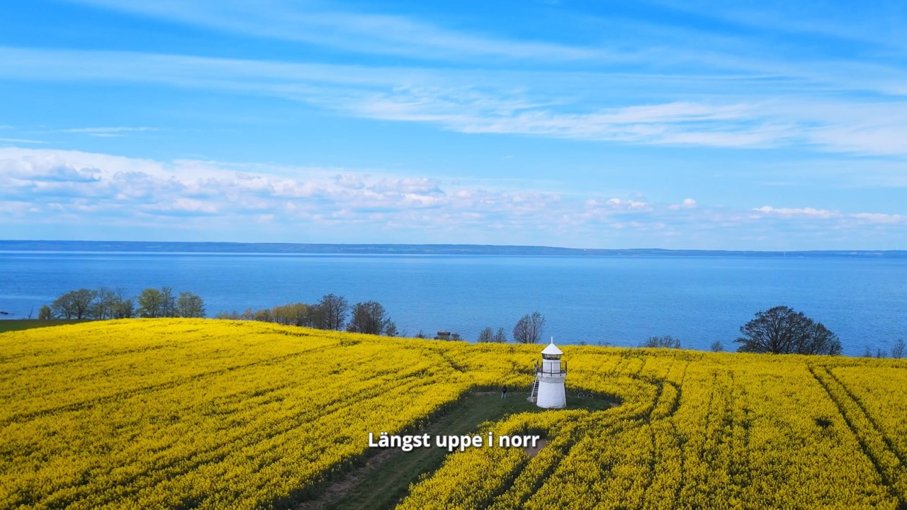 A lighthouse in a blazing yellow canola field by the lake — from the pilot of A Thousand and One Journeys