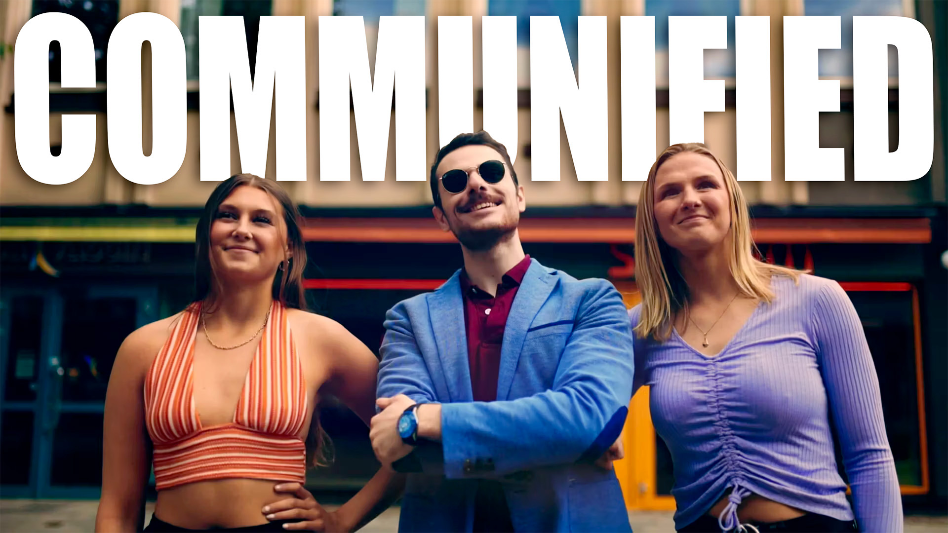 Stillbild ur Communifieds lanseringsfilm: tre unga personer framför ett café, med ordet COMMUNIFIED i stora vita bokstäver.