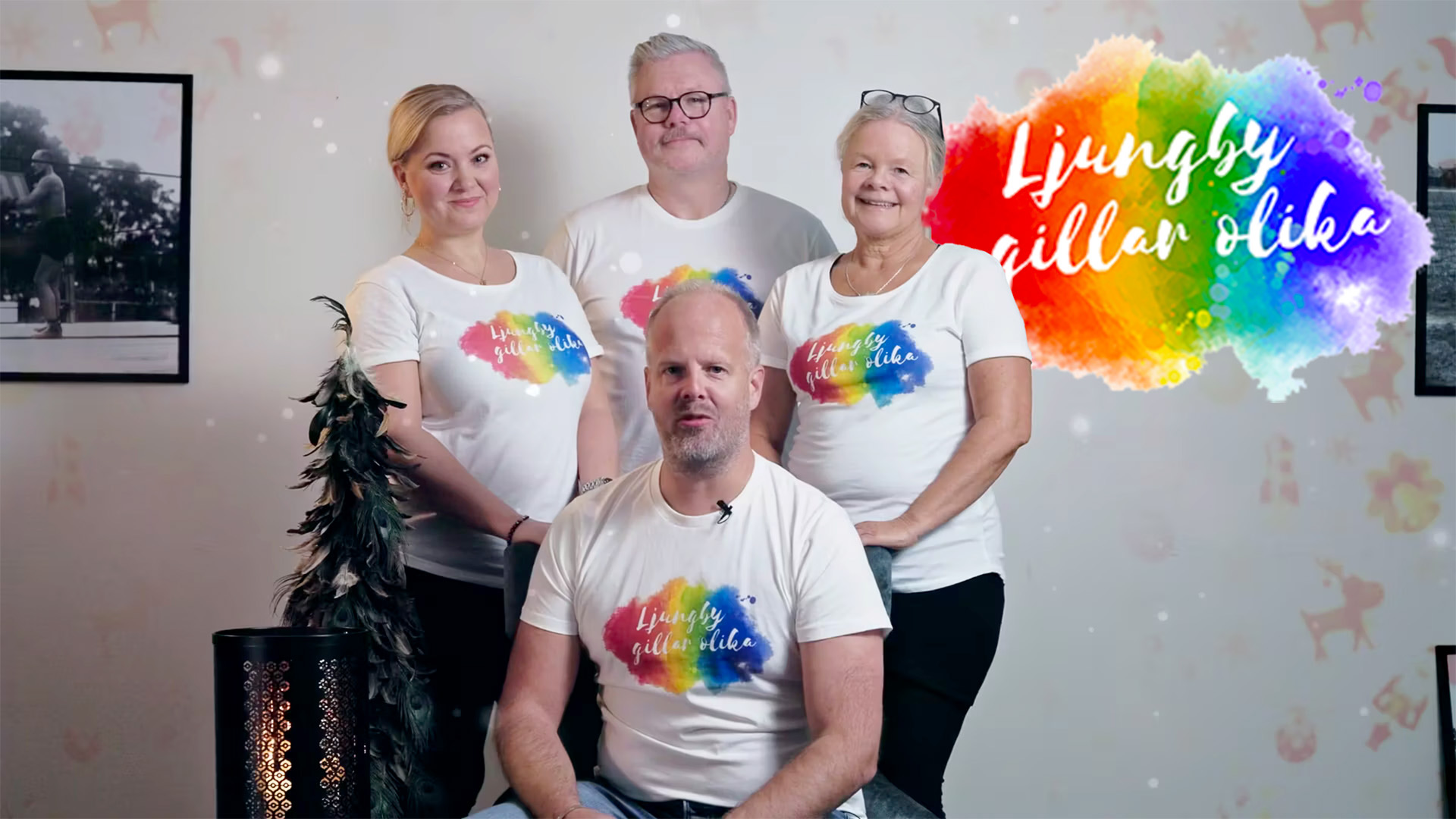Fyra personer i vita tröjor med regnbågsfärgat tryck står framför en vägg med julpynt, bredvid texten Ljungby gillar olika.