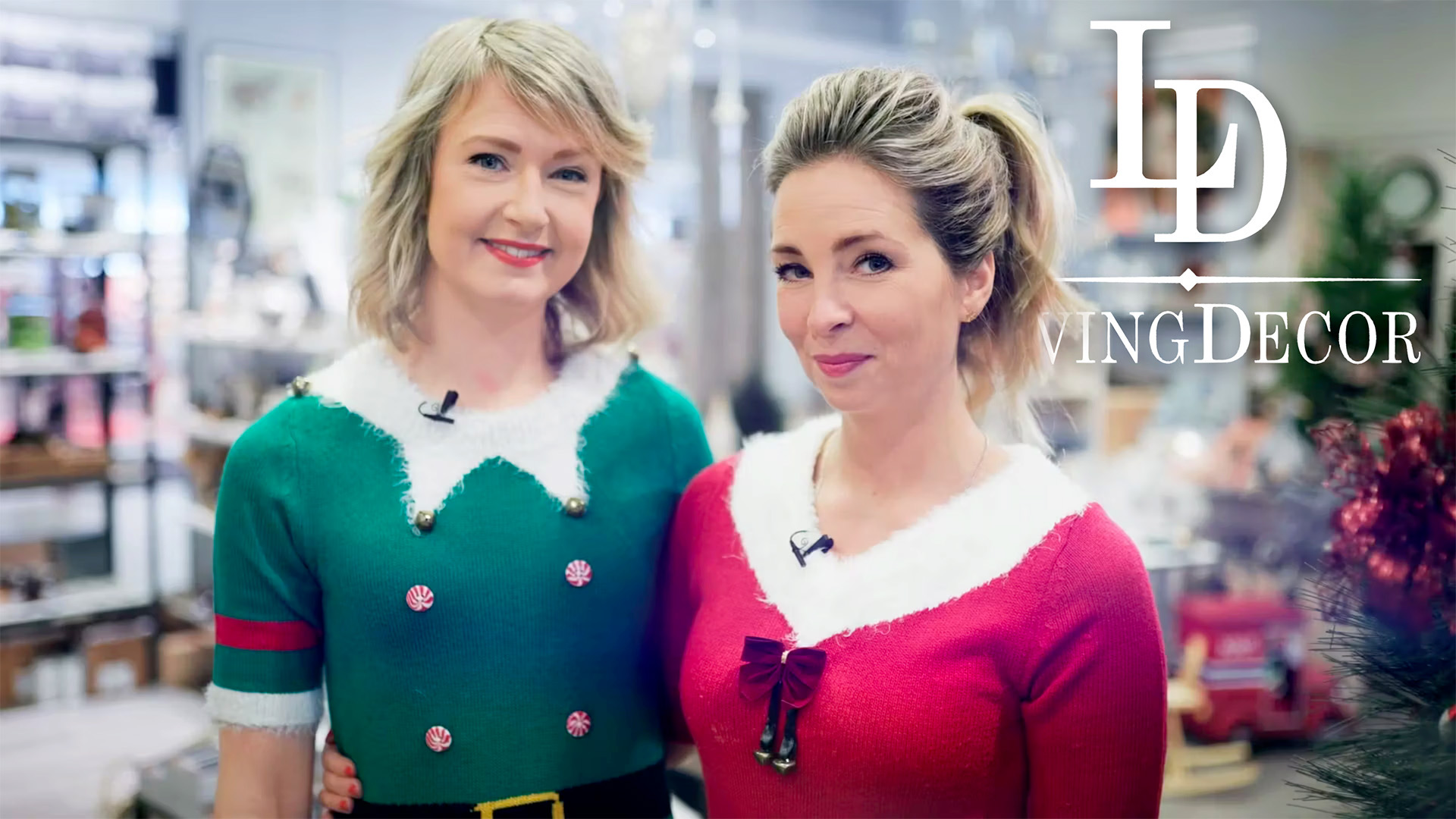 Två kvinnor i röd och grön jultröja ler i inredningsbutiken, med Living Decors logotyp.