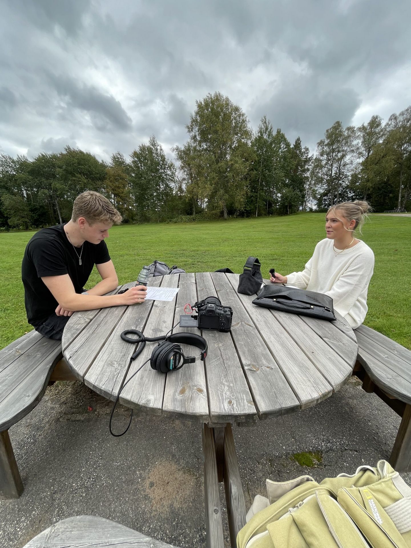 Preparing for an interview at an outdoor table — camera, microphone and question sheet